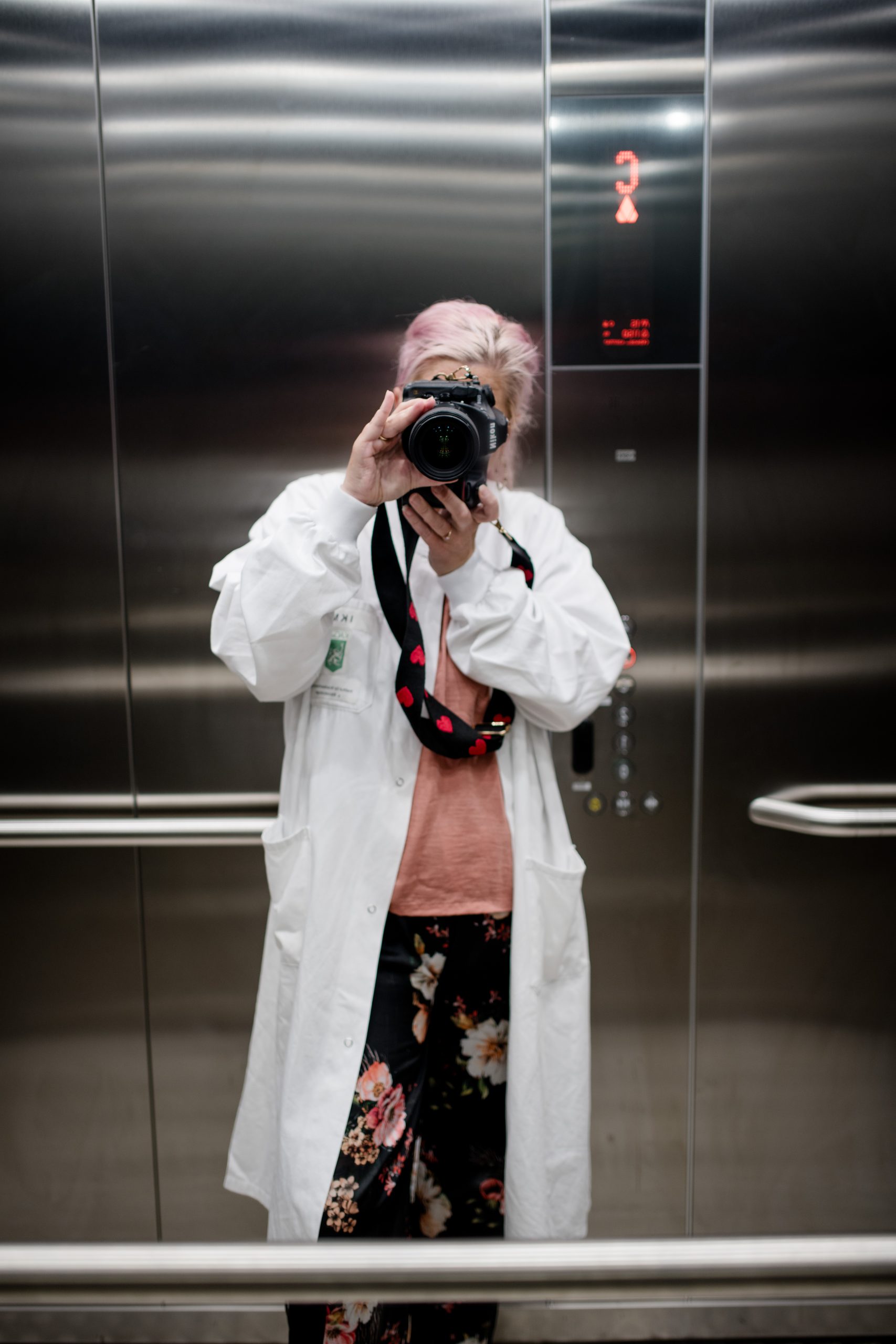 Fotografin Conny in einem Aufzug mit weißem Mantel bekleidet.