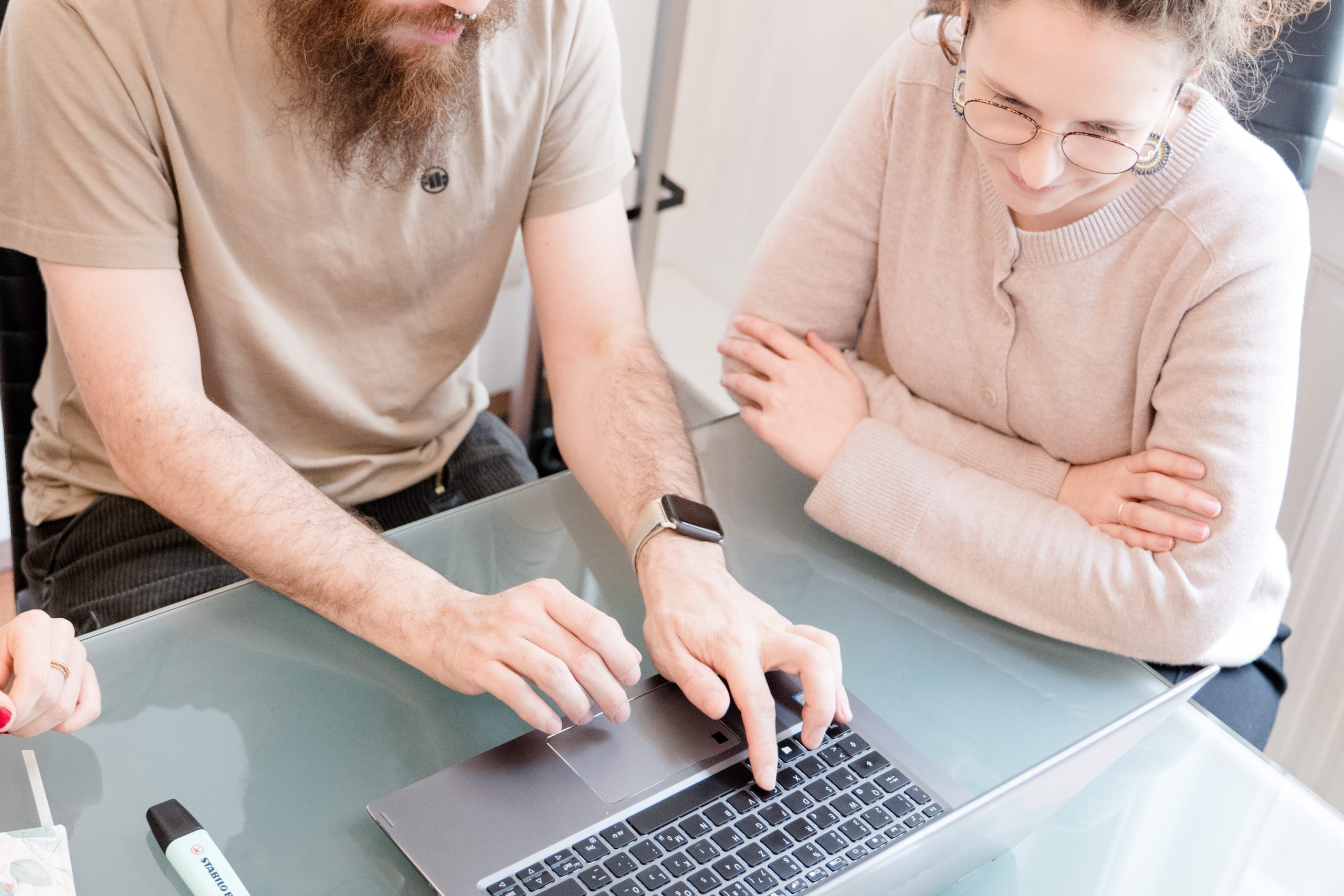 Drei Kolleg:innen bei der Arbeit. Zu sehen ist ein Laptop und Hände.